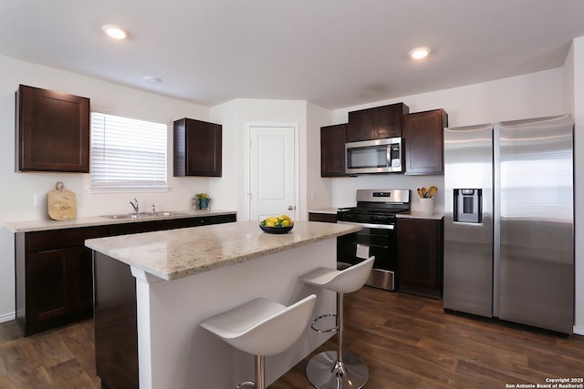 kitchen featuring dark wood-type flooring, a kitchen breakfast bar, sink, a kitchen island, and stainless steel appliances