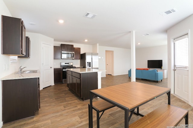 kitchen featuring a center island, sink, stainless steel appliances, hardwood / wood-style floors, and dark brown cabinets