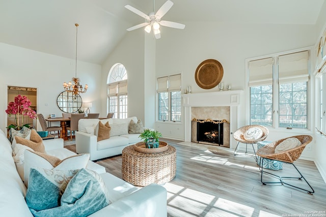 living room featuring a fireplace, plenty of natural light, high vaulted ceiling, and light hardwood / wood-style flooring