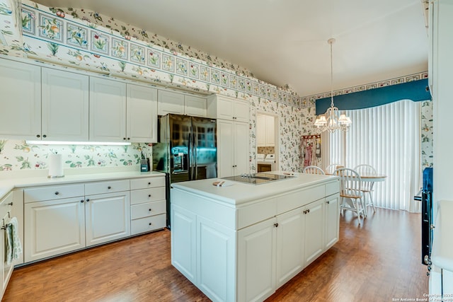 kitchen featuring pendant lighting, a center island, white cabinets, black appliances, and a notable chandelier