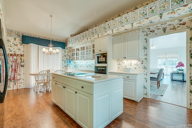 kitchen with pendant lighting, ceiling fan with notable chandelier, a kitchen island, and hardwood / wood-style flooring