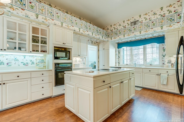 kitchen featuring a center island, white cabinets, black appliances, and light wood-type flooring