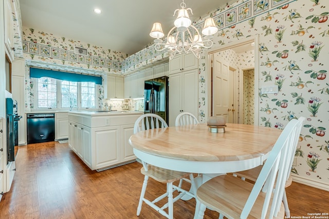 dining area with light hardwood / wood-style floors, an inviting chandelier, and sink