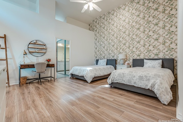 bedroom with a towering ceiling, light hardwood / wood-style floors, and ceiling fan