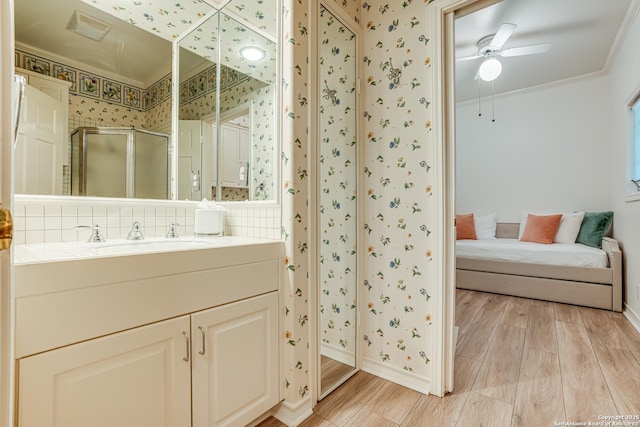 bathroom with an enclosed shower, vanity, ceiling fan, crown molding, and wood-type flooring