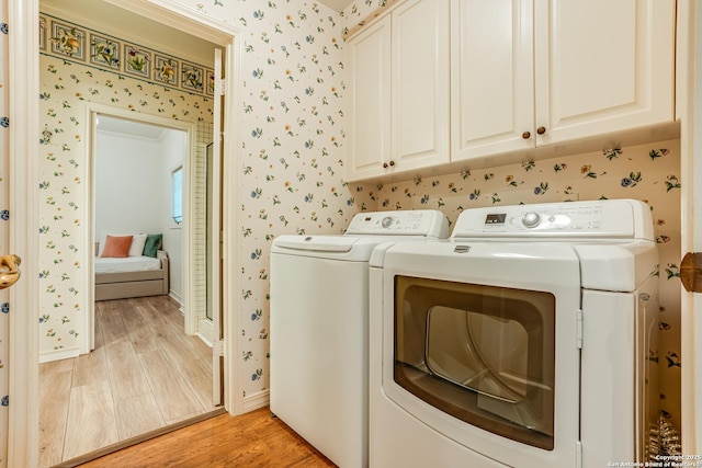 laundry room featuring washer and dryer, light hardwood / wood-style floors, and cabinets