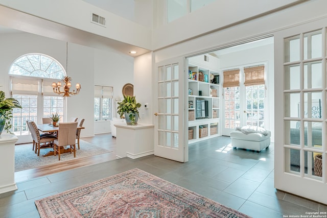 interior space with an inviting chandelier, a high ceiling, and french doors