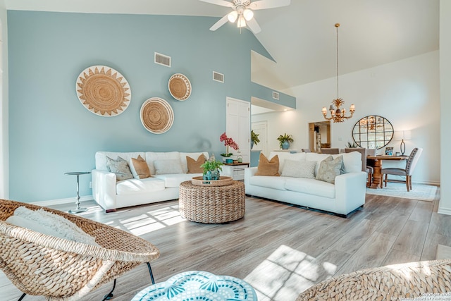 living room featuring high vaulted ceiling, light hardwood / wood-style floors, and ceiling fan with notable chandelier