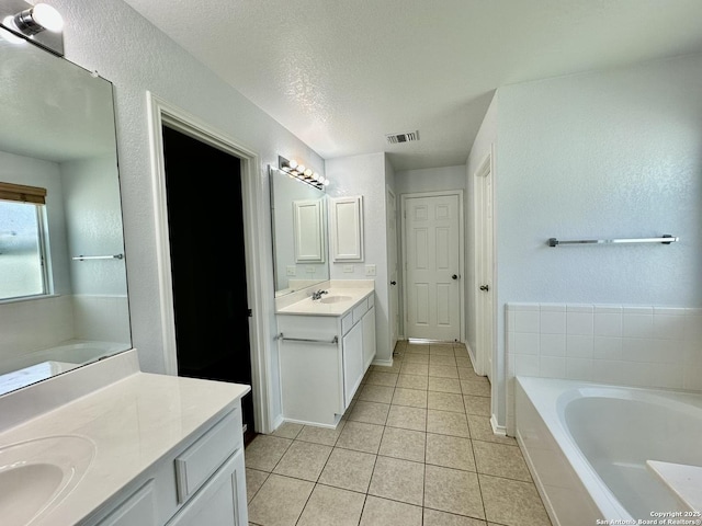 bathroom featuring vanity, a textured ceiling, tile patterned floors, and a bathtub