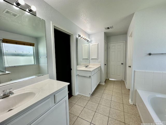 bathroom with vanity, a bath, a textured ceiling, and tile patterned floors