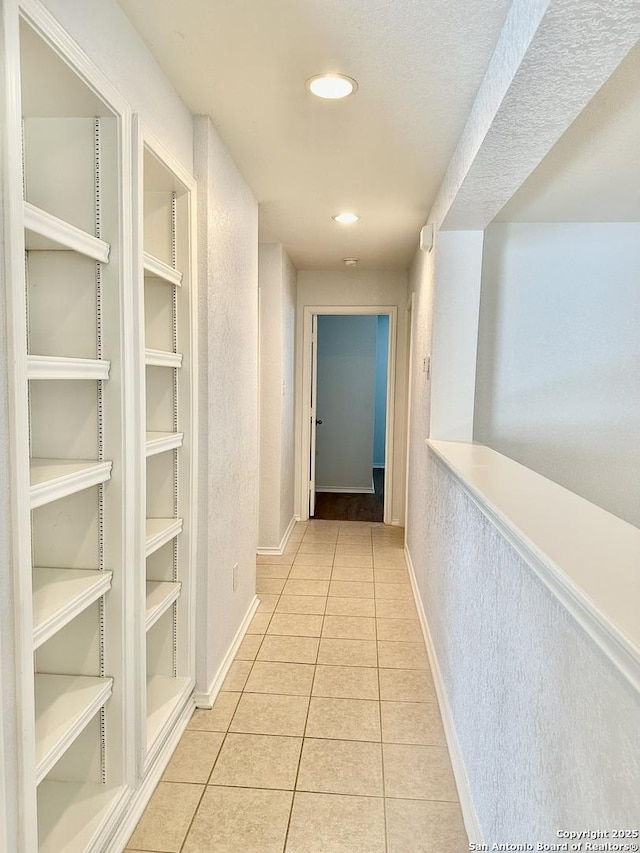 corridor featuring light tile patterned floors and built in shelves