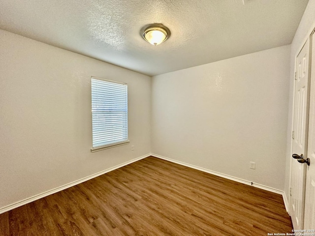 unfurnished room featuring dark wood-type flooring and a textured ceiling