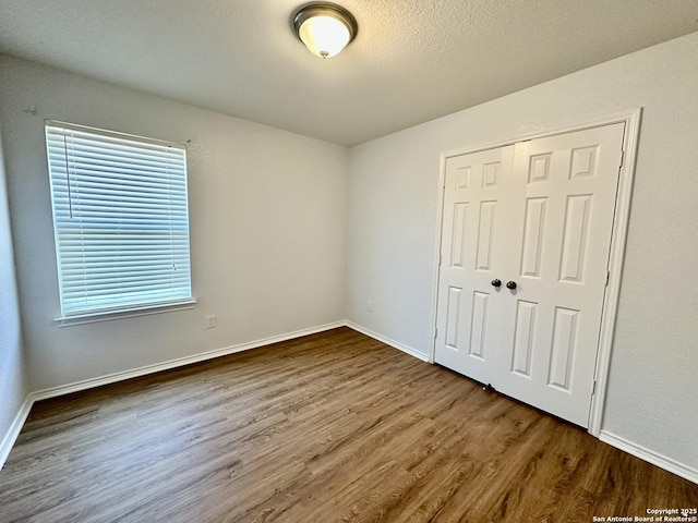 unfurnished bedroom with a textured ceiling, a closet, and dark hardwood / wood-style floors