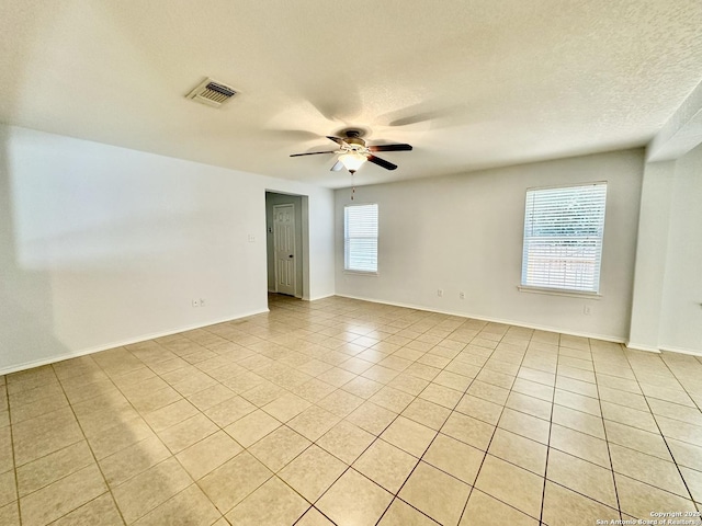 tiled spare room with ceiling fan and a textured ceiling