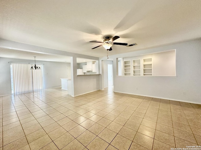 unfurnished room featuring light tile patterned floors, ceiling fan with notable chandelier, and built in shelves