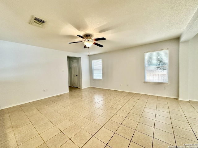 tiled spare room featuring ceiling fan, plenty of natural light, and a textured ceiling