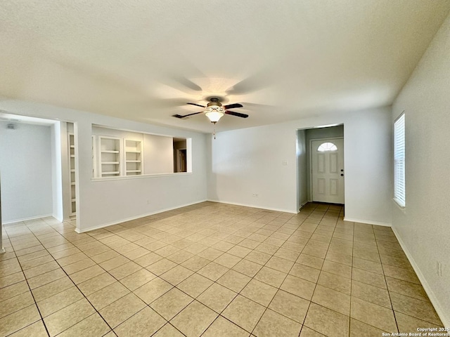 spare room with light tile patterned floors, built in features, and ceiling fan