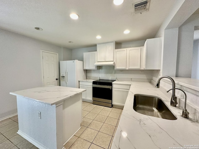 kitchen featuring sink, white refrigerator with ice dispenser, light tile patterned floors, electric stove, and white cabinetry