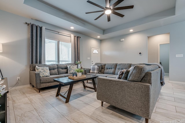 living room featuring a tray ceiling and ceiling fan