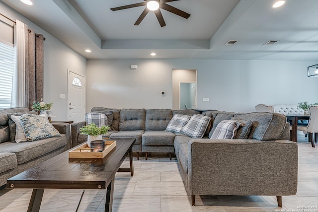 living room featuring a tray ceiling and ceiling fan