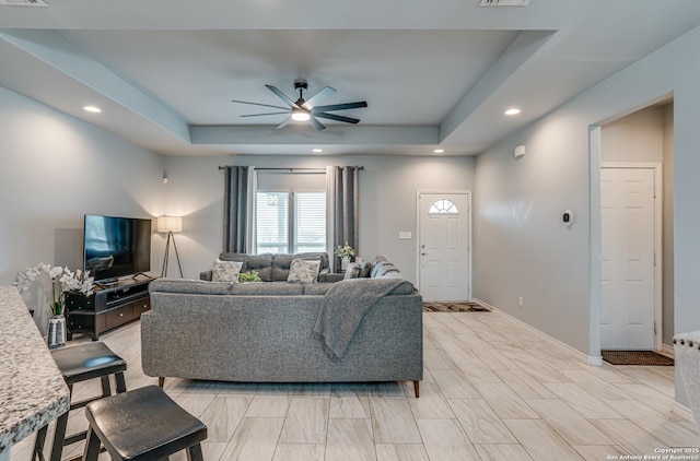 living room featuring ceiling fan and a tray ceiling