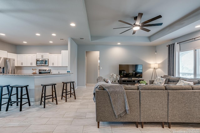 living room featuring a tray ceiling and ceiling fan