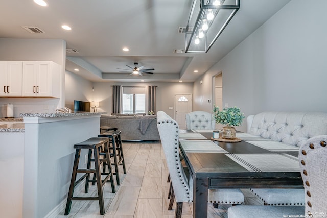 dining area featuring a raised ceiling and ceiling fan