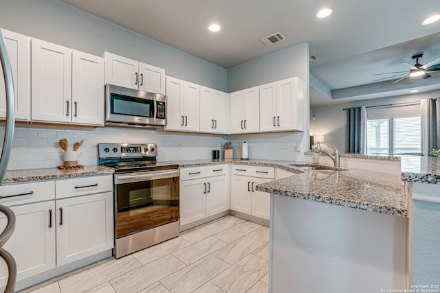 kitchen featuring appliances with stainless steel finishes, light stone counters, white cabinetry, and sink