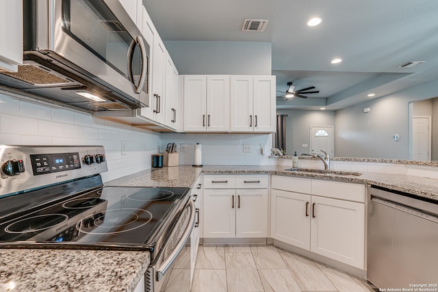 kitchen featuring sink, ceiling fan, light stone countertops, appliances with stainless steel finishes, and white cabinetry