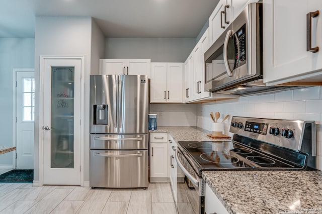 kitchen with white cabinets, appliances with stainless steel finishes, and light stone counters