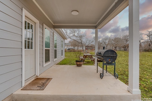 patio terrace at dusk featuring area for grilling and a yard