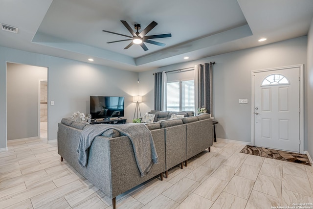 living room featuring ceiling fan and a raised ceiling