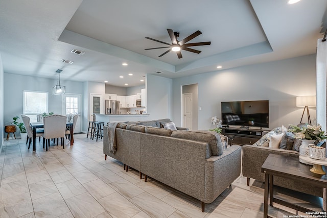 living room with a tray ceiling and ceiling fan