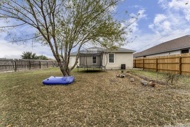 rear view of property featuring a yard and a trampoline