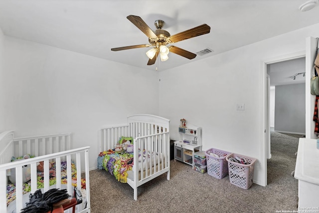 carpeted bedroom with ceiling fan and a nursery area