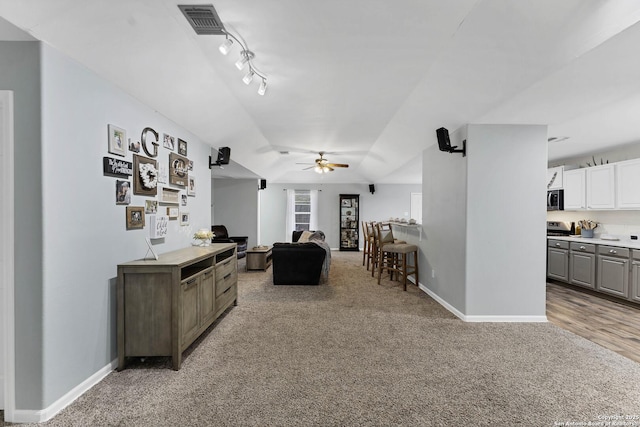 carpeted living room with ceiling fan, track lighting, and vaulted ceiling