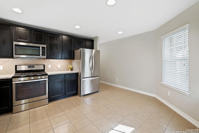 kitchen featuring appliances with stainless steel finishes, backsplash, light stone counters, and light tile patterned flooring