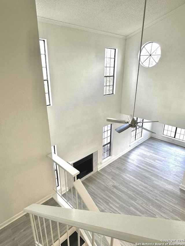 staircase featuring a textured ceiling, ceiling fan, wood-type flooring, and ornamental molding