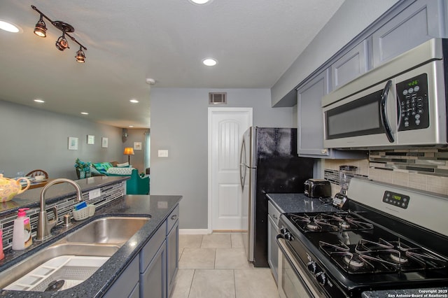 kitchen with gray cabinetry, dark stone counters, sink, appliances with stainless steel finishes, and light tile patterned flooring