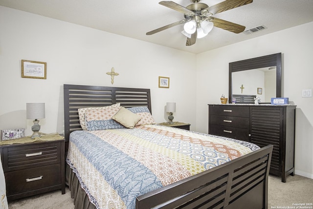 bedroom featuring ceiling fan, light colored carpet, and a textured ceiling