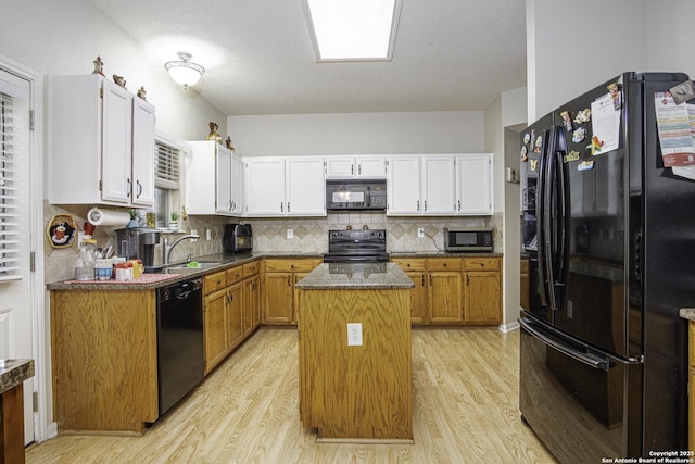 kitchen with white cabinets, sink, a kitchen island, and black appliances