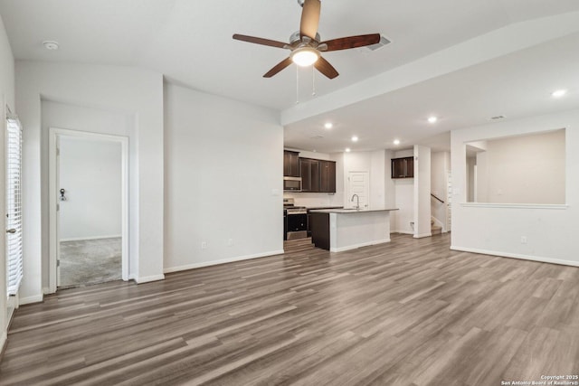 unfurnished living room featuring hardwood / wood-style floors, ceiling fan, and sink