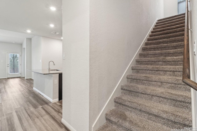 stairway featuring hardwood / wood-style floors and sink