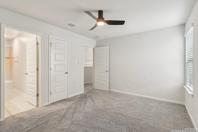 unfurnished bedroom featuring ensuite bathroom, a closet, ceiling fan, and light carpet