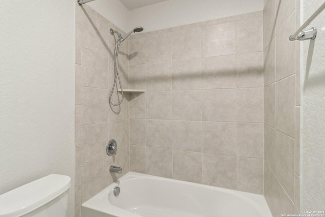 bathroom featuring toilet and tiled shower / bath