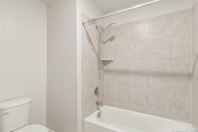 bathroom with tiled shower / bath combo and toilet