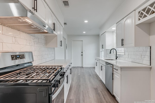 kitchen with stainless steel appliances, sink, light hardwood / wood-style flooring, and white cabinets