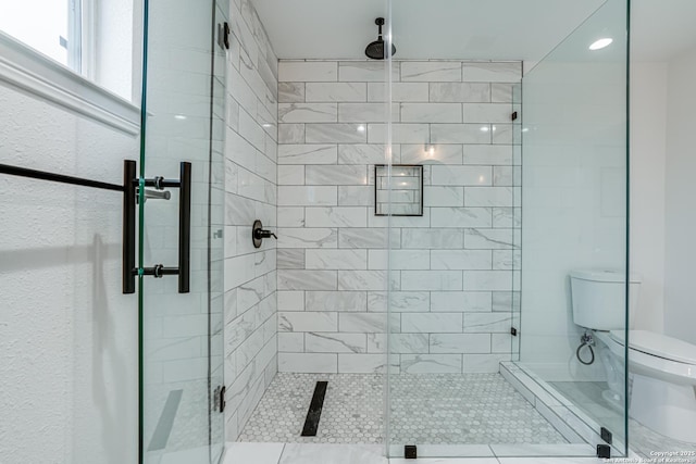 bathroom featuring a shower with shower door and toilet