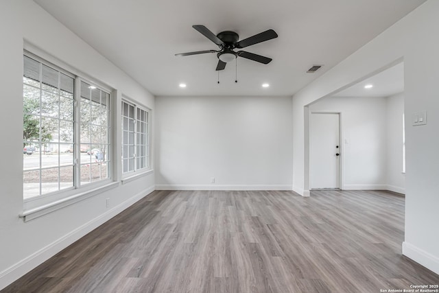 spare room featuring ceiling fan, a healthy amount of sunlight, and light wood-type flooring