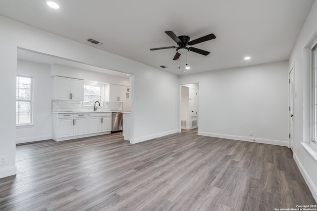 unfurnished living room featuring ceiling fan, sink, and light wood-type flooring